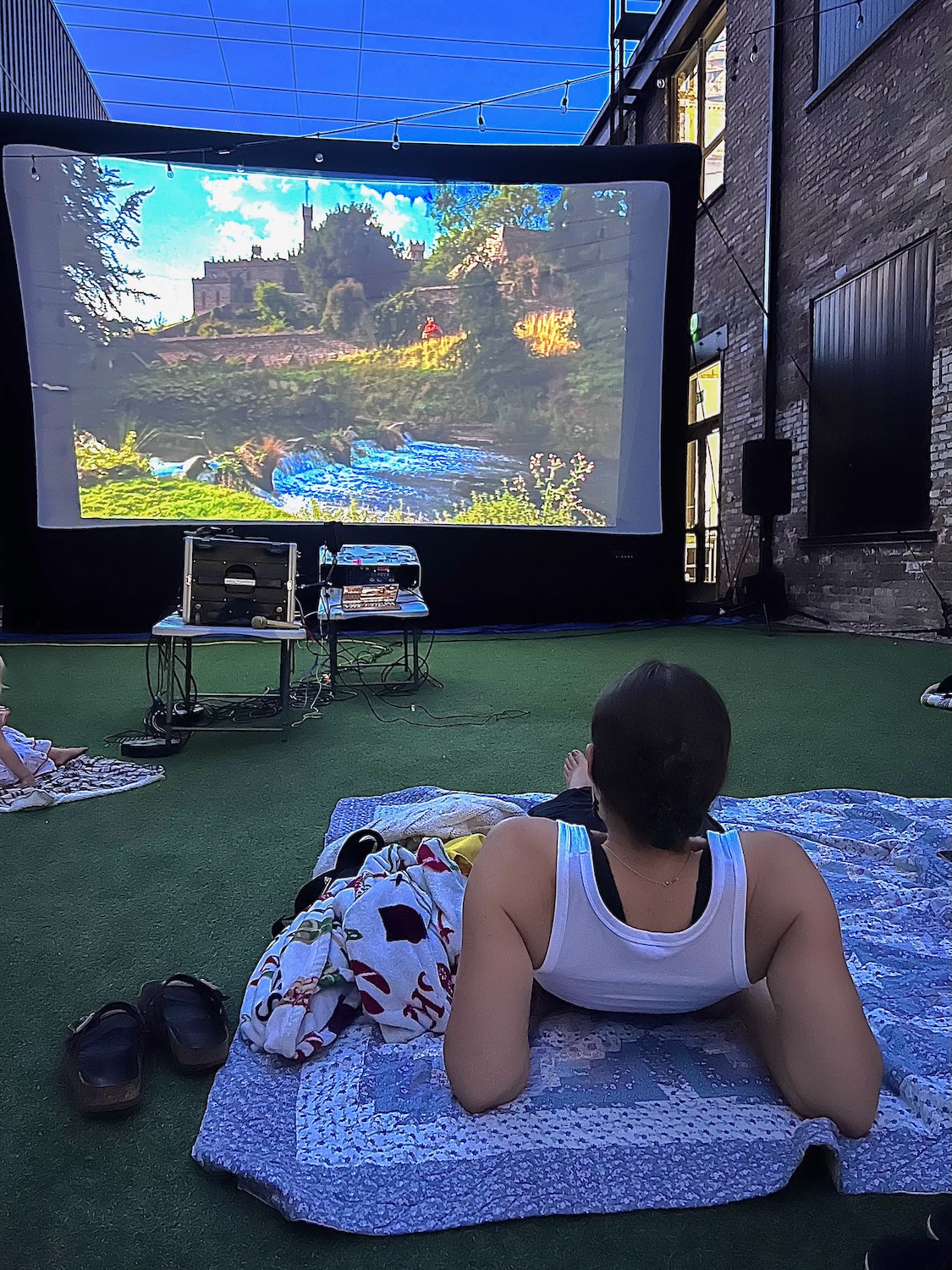 Guest watching an outdoor movie on a blanket during Movies in The Alley at Woodbine Food Hall
